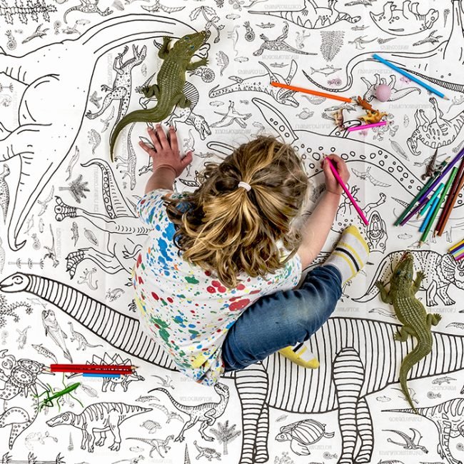 girl colouring in a giant poster eggnogg dinosaurs