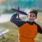 child flying a foam glider